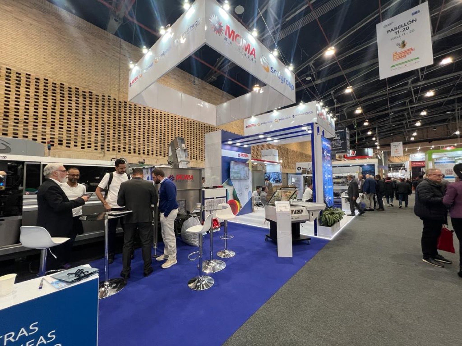 Visitantes conversando con asesores de MOMA en el stand